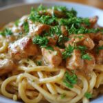 A close-up of Crock Pot Creamy Cajun Chicken Pasta, featuring pasta coated in a rich sauce with tender chicken pieces and fresh parsley garnish.