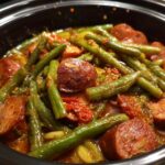 Close-up of Crockpot Kielbasa and Green Beans simmering in a slow cooker with a rich tomato-based sauce.