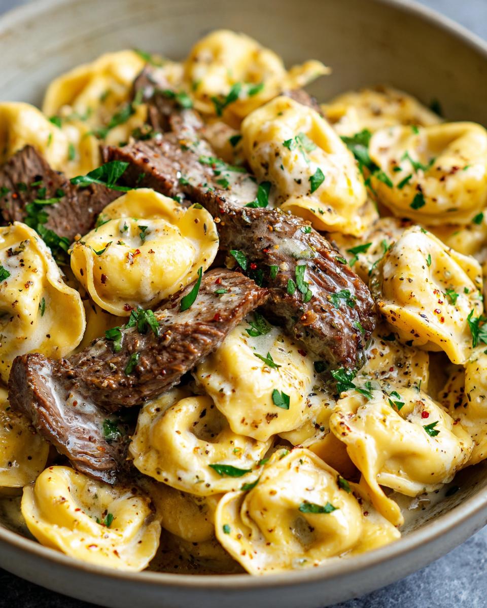 Close-up of Garlic Steak Tortellini with tender steak slices and a rich cream sauce, garnished with parsley.