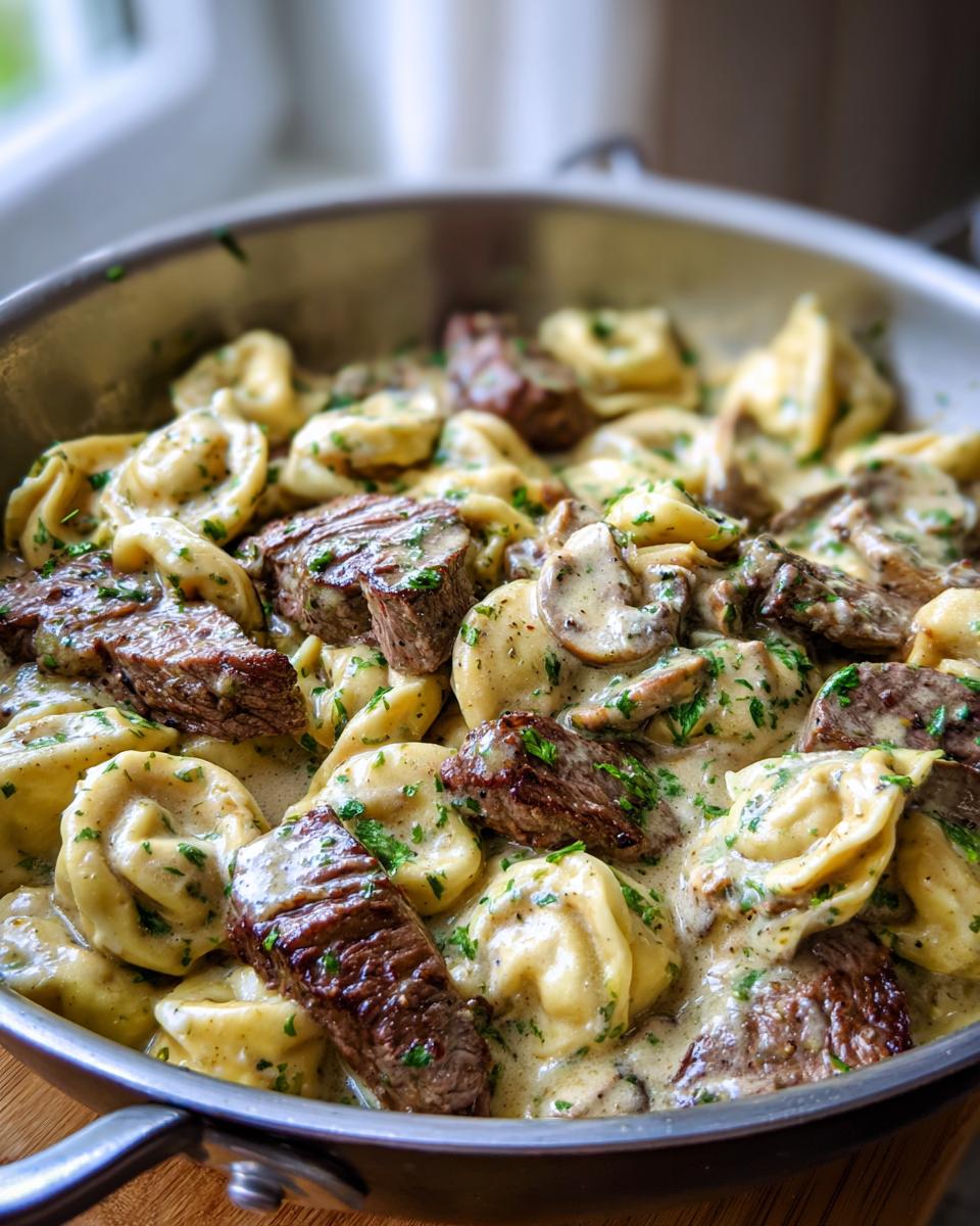 Close-up of Garlic Steak Tortellini in a creamy sauce with mushrooms and parsley.