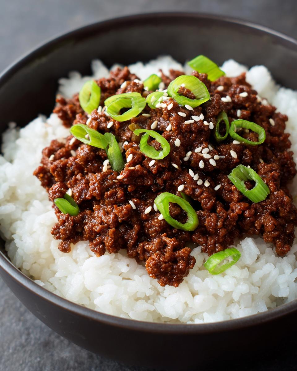 A close-up of a Korean Ground Beef Bowl topped with fresh scallions and sesame seeds, served over white rice.