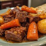 A close-up of a plate filled with tender Korean Style Pot Roast, chunks of carrots, and whole potatoes in a rich sauce.