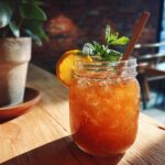 A refreshing glass of peach iced tea slush with a lemon slice and mint, perfect for hot afternoons.