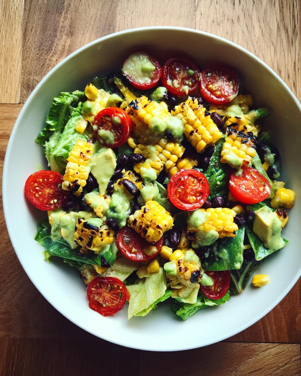 A vibrant Summer Salad with Grilled Corn and Avocado Lime Dressing, featuring lettuce, cherry tomatoes, black beans, and grilled corn.